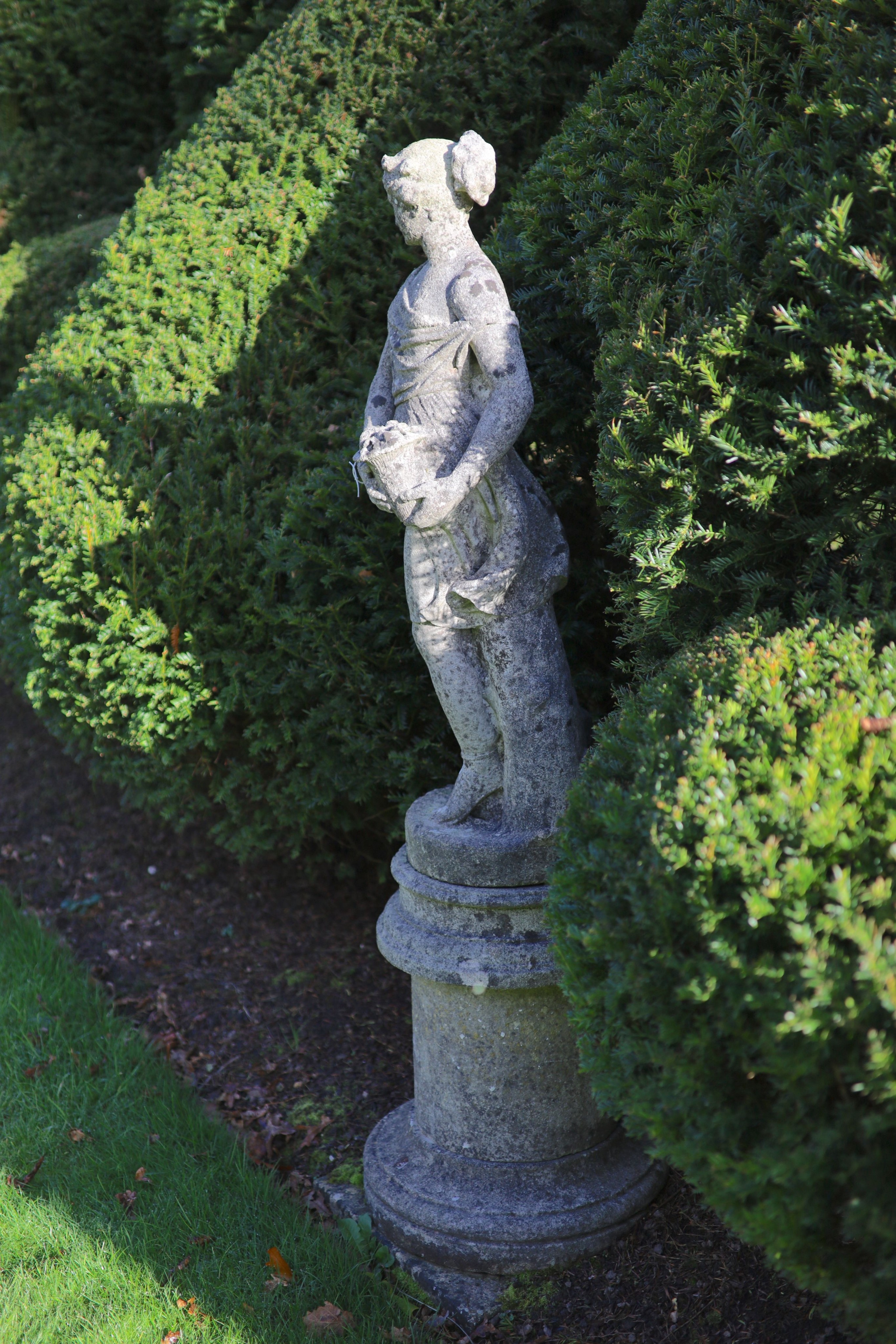 A reconstituted stone garden statue modelled as Flora, on turned socle, height overall 154cm